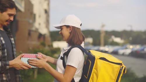 Delivery Woman Gives Gift to Young Adult Man