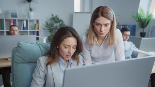 Two Young Businesswomen Working Discussing Use Laptop Computer In Modern Office On Background People