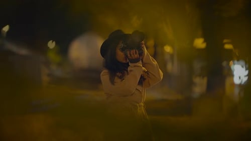 Woman Photographs with DSLR Camera in City Park at Night