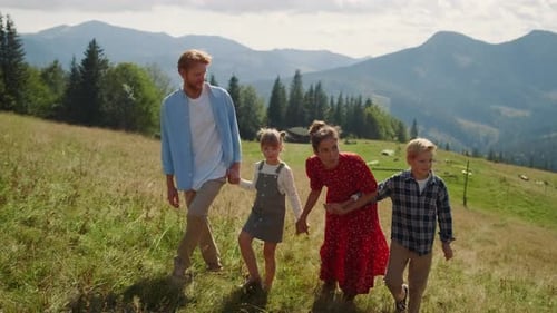 Happy Family Enjoying Walk Together in Mountains Summer Holiday. Relaxed Parents Pointing