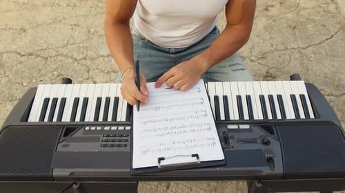 Composer Writing Musical Notes Outdoors on Keyboard
