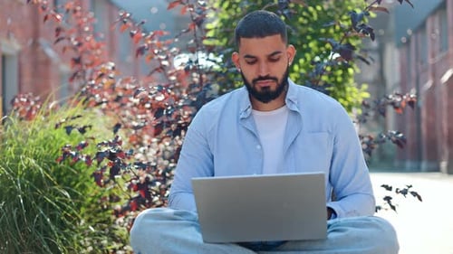 Bearded Man Using Laptop Outdoors in Urban Setting