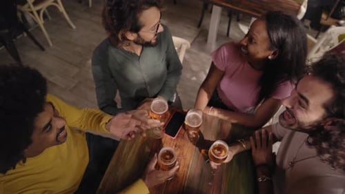 Happy Friends Toasting With Beer at Bar at Night