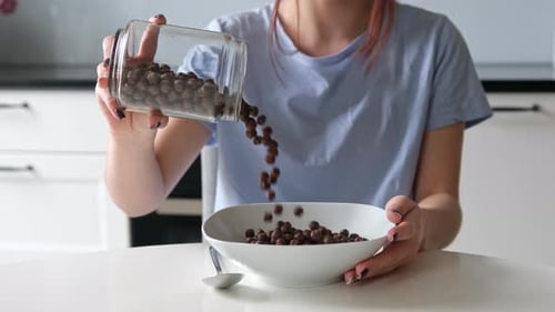 Woman Pours Cereal into Bowl for Breakfast