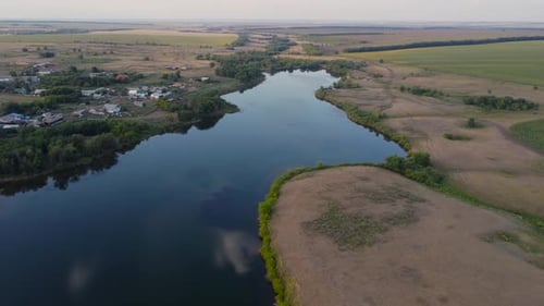A Serene River Weaving Through Lush Fields in a Beautiful Landscape Seen From a Drone