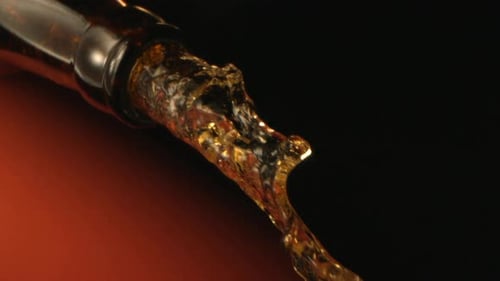 Beautiful Yellow Liquid Is Pouring Down From A Bottle In High Speed Motion On Dark Background