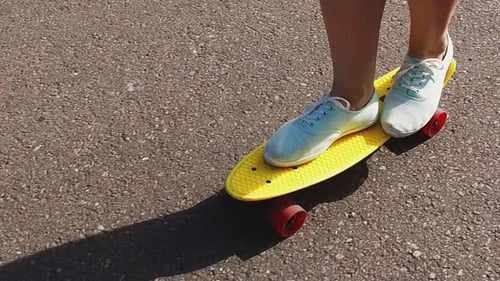 Feet Standing on Yellow Skateboard on Asphalt