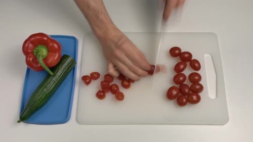 Mann schneidet Pflaumentomaten mit einem Messer. Ansicht von oben nach unten. Amateurkoch. Zeitraffer