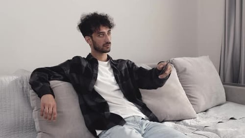 Man Relaxing on Couch Holding Remote Control