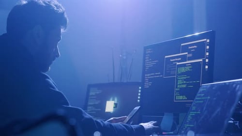 A Focused Programmer Works Intensely on Intricate Tasks Using Multiple Screens in a Dim Room