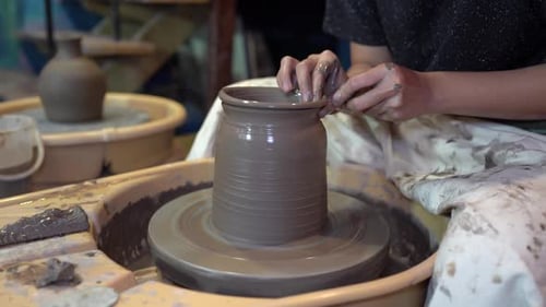 Vue rapprochée des mains du potier travaillant avec de l'argile humide sur une roue de poterie pour fabriquer une argile