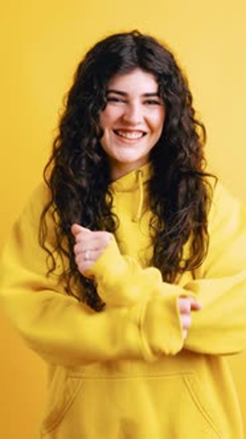 Smiling woman in yellow hoodie on yellow background