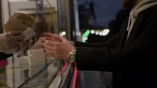Street food - a man picks up his pita shawarma doner kebab from the store