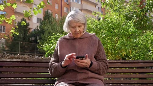 Senior Woman Using Smartphone on Park Bench