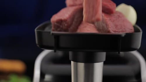 meat grinder's tray full of meat, woman's hand puts meat into opening