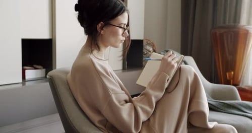 Woman Writing in Notebook in Home Setting