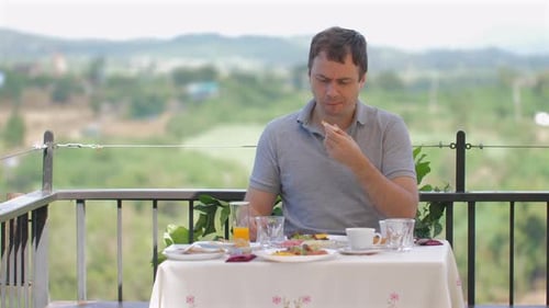Man Enjoying Breakfast Meal While Sitting at Outdoor Restaurant Table