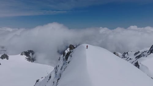 A man climbing Snowy Mountains in the remote wild reaches of nature. Majestic terrain on a beautiful