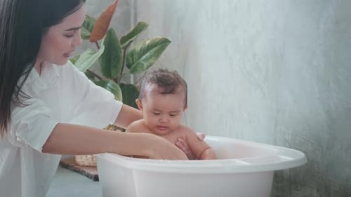 Mother Giving Happy Baby a Bath at Home