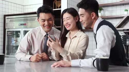 Young Adults Looking at Phone Celebrating Success in Cafe