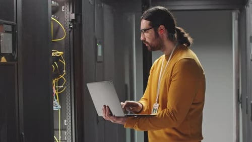 IT Technician with Laptop Checking Work of Hardware in Data Center