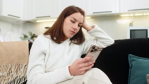 Young Woman Doomscrolls News on Smartphone Bored Tired Stressed Mood Swipes Feed Unhappy and Drained