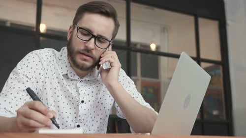Eine trendige erwachsene männliche Person telefoniert im Arbeitsbereich