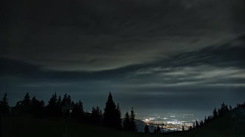 Captivating night timelapse: Mountains adorned by moving clouds in a celestial dance, revealing the