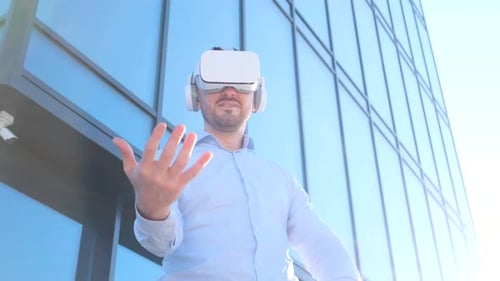 Business Man Uses Virtual Reality Glasses He is Waving His Hands on the Background of the Office