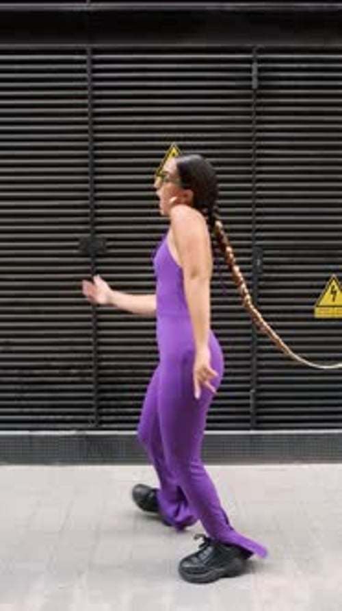 Energetic Woman Dancing in Purple Jumpsuit on City Street