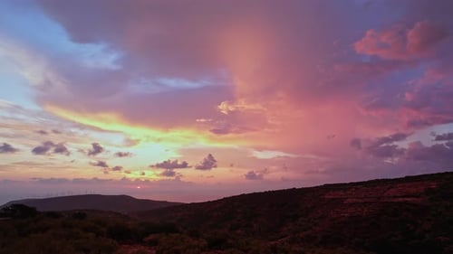 Vibrant sunset over rolling hills with colorful clouds in the evening sky