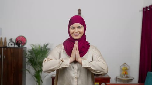 Muslimische Frau im Hijab-Schal begrüßt Namaste