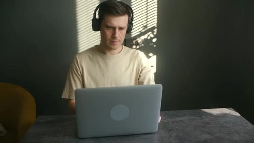 Man Working on Laptop with Headphones at Home