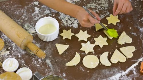 Preparing Raw Cutout Sugar Cookies with a Brush