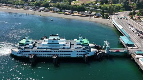 Panning drone shot of cars loading onto a public ferry for commuting.