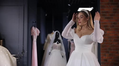 Linda noiva loira elegante usando um vestido de noiva em um provador em um salão de noivas