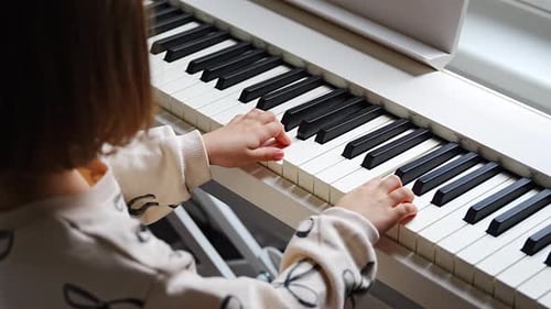 Child Plays Piano Indoors in Natural Light