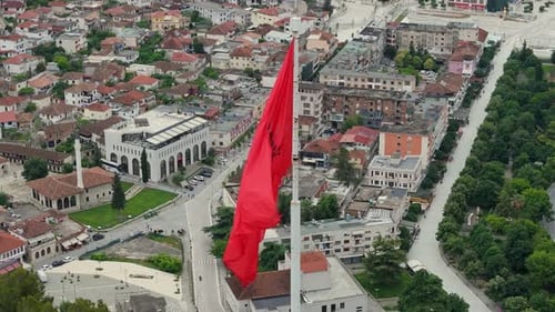 Aufnahme der Umlaufbahn um die albanische Flagge über Ziegeldächern von Häusern, Moscheen und Minaretten in Berat, Alban