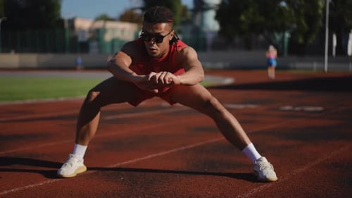 Athlete Stretching at Outdoor Running Track on Sunny Day