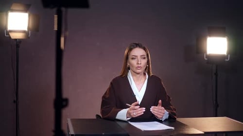 Confident Woman Speaking at Desk in Studio Setting