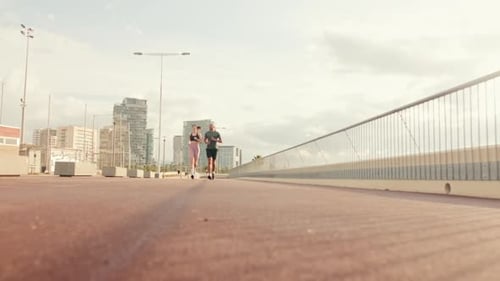 Young joyful active couple jogging together along beautiful seafront. Ground focus