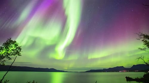 Northern lights timelapse over calm lake in Abisko, Sweden
