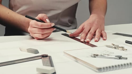 Junge Künstlerin zeichnet Gebäude mit Bleistift mit Lineal auf weißem Papier Der Designer oder