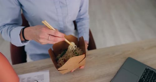 Food, office and hands for night, laptop and person with noodles for overtime