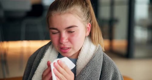 Fille, enfant et nez qui se mouche sur le canapé avec un mouchoir, une couverture et un repose-pieds pour se rétablir de la grippe dans le salon