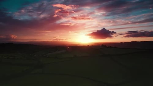 Stunning Pink and Orange Sunrise or Sunset Casts Its Glow Over Vibrant Green Fields Alongside a