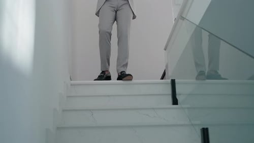 Man in Gray Suit Walks Down Marble Stairs