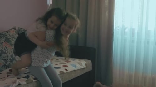 Two Happy Girls Hugging Each Other on Sofa