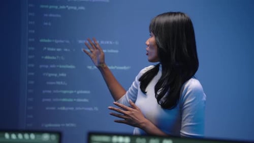 Asian Tech Speaker Explaining Programming In Front Of Code Wall