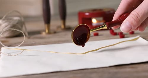 Hand Sealing Envelope with Red Wax on Desk